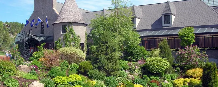 Casino de Charlevoix in La Malbaie, a grey-roofed building with a round turret behind landscaped rock gardens